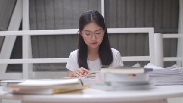 亚洲学生妇女读图书馆的书籍在大学 年轻的本科生女孩做家庭作业 读课本 努力学习知识和教育在课桌在大学校园的概念 — 图库视频影像