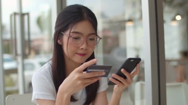 自由职业者亚洲女性在咖啡店网上购物 年轻的亚洲女孩使用手机 信用卡购买和购买电子商务互联网在户外咖啡厅的餐桌上在晚上的概念 慢动作 — 图库视频影像