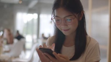 Ofiste cep telefonu kullanan serbest Asyalı kadınlar. Genç Japon Asya Kız işyeri kavramı masada internet üzerinden sosyal medya kontrol akıllı telefon kullanarak. Yavaş çekim ve Çekimi kapat.