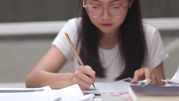 亚洲学生妇女读图书馆的书籍在大学 年轻的本科生女孩做家庭作业 读课本 努力学习知识和教育在课桌在大学校园的概念 — 图库视频影像