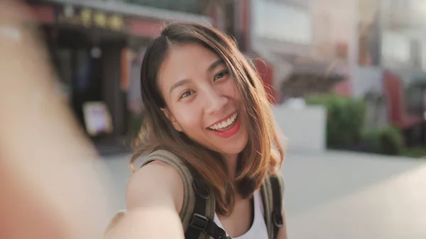 陽気な美しい若いアジア バックパッカー ブロガーの女性が北京で中華街で旅行中 selfie を取ってスマート フォンを使用して。ライフ スタイルはバックパック観光旅行休暇の概念です。ビューのポイント. — ストック写真