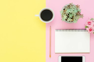 Ofis Masası adlı kullanıcının alanı - düz çalışma beyaz boş defter sayfası, kahve fincanı ve sahte telefon pastel arka plan üzerinde bir çalışma alanının en iyi görünümü yatırın. Pastel pembe sarı renk arka plan boşluk kavramı.