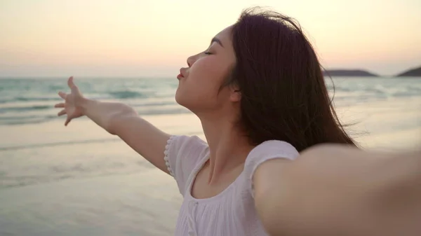 Turista asiatica selfie donna sulla spiaggia, giovane bella femmina felice sorridente utilizzando il telefono cellulare prendendo selfie sulla spiaggia vicino al mare quando il tramonto della sera. Stile di vita le donne viaggiano sul concetto di spiaggia . — Foto Stock