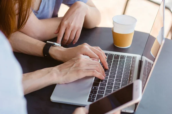 Aziatische jonge vrouwen die op laptop met behulp van smartphone kijken en drinken koffie zittend in een café werkt. Mededeling van de vrouwen van de levensstijl en het werken in koffie winkelconcept. — Stockfoto