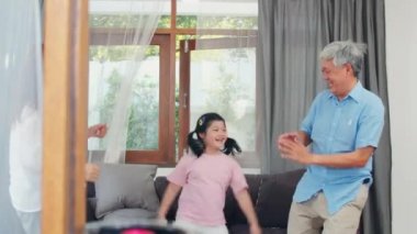 Asyalı dedesi ve torunu müzik dinlemek ve evde birlikte dans. Üst düzey Çinli, büyükbaba ve büyükanne mutlu oturma odası kavramı genç kız ile dinlenmek aile zaman harcamak. Yavaş çekim.