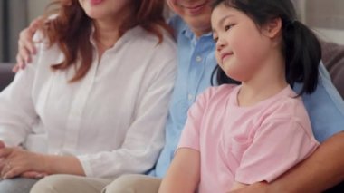 Asyalı büyükanne ve büyükbaba evde torunu ile konuşuyor. Üst düzey Çin, eski nesil, dedesi ve büyükanne aile zaman oturma odası kavramı kanepede genç kız çocuk ile dinlenmek. Yavaş çekim.