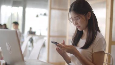 Ofiste cep telefonu kullanan serbest Asyalı kadınlar. Genç Japon Asya Kız işyeri kavramı masada internet üzerinden sosyal medya kontrol akıllı telefon kullanarak. Yavaş çekim.