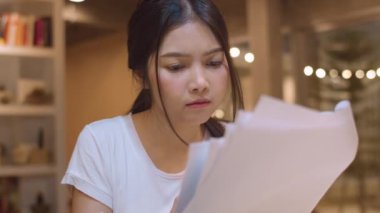 Asyalı öğrenci kadınlar üniversitede kütüphanede kitap okuyor. Genç lisans kız ev ödevi yapmak, ders kitabı okumak, üniversite kampüsünde ders masasında bilgi için çok çalışmak fazla mesai gece. Yavaş çekim.