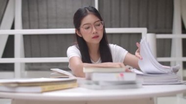 Asyalı öğrenci kadınlar üniversitede kütüphanede kitap okuyor. Genç lisans kız ev ödevi yapmak, ders kitabı okumak, üniversite kampüs kavramı ders masasında bilgi ve eğitim için çok çalışmak.