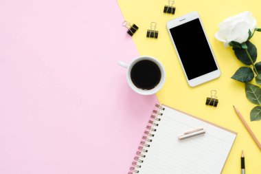 Ofis Masası adlı kullanıcının alanı - düz çalışma beyaz boş defter sayfası, kahve fincanı ve sahte telefon pastel arka plan üzerinde bir çalışma alanının en iyi görünümü yatırın. Pastel pembe sarı renk arka plan boşluk kavramı.