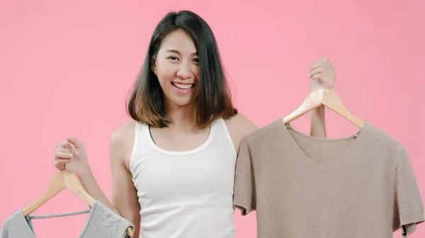 Ung vacker fashionabla asiatisk kvinna väljer kläder i casual kläder över rosa bakgrund Studio skott. Glad leende bedårande glad kvinna gläds framgång. — Stockfoto