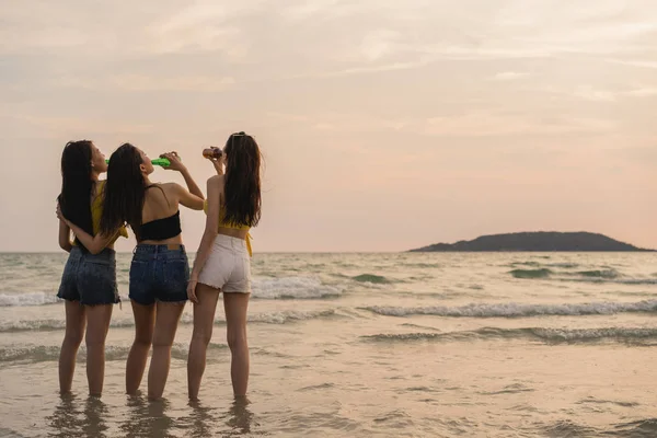 Grupo de meninas adolescentes asiáticas que fazem festa celebrando na praia, amigos felizes bebendo cerveja na praia no mar quando o sol se põe à noite. Atividade ao ar livre amigos viagem férias verão conceito . — Fotografia de Stock
