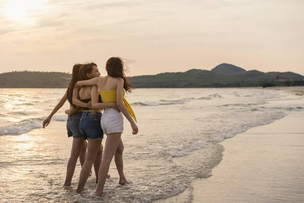 Grupo de três jovens mulheres asiáticas andando na praia, amigos felizes relaxar se divertindo brincando na praia perto do mar quando o sol se põe à noite. Estilo de vida amigos viagem férias na praia verão conceito . — Fotografia de Stock