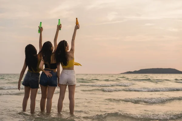 Grupo de meninas adolescentes asiáticas que fazem festa celebrando na praia, amigos felizes bebendo cerveja na praia no mar quando o sol se põe à noite. Atividade ao ar livre amigos viagem férias verão conceito . — Fotografia de Stock