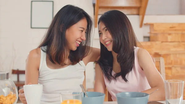 Asiática lesbianas lgbtq mujeres pareja tener desayuno en casa, joven asiática amante femenina sensación feliz bebida jugo, maíz copos cereal y leche en bowl en mesa en cocina en la mañana concepto . —  Fotos de Stock