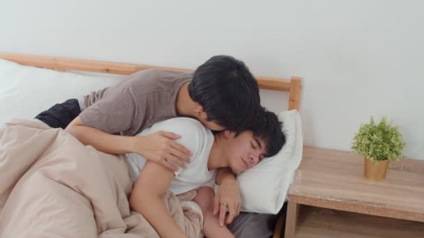 アジアのゲイのカップルは 自宅でベッドの上でキスと抱擁 若いアジアのLgbtqの男性は 朝のコンセプトで自宅の寝室で目を覚ました後 一緒にロマンチックな時間を過ごす幸せなリラックスした時間を過ごします スローモーションショット — ストック動画