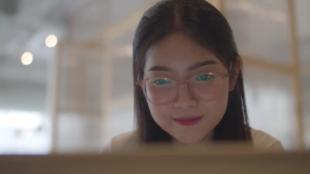 Szabadúszó ázsiai nők dolgoznak laptop az irodában. Fiatal ázsiai üzleti lány a számítógép segítségével a kereskedelem, küldjön e-mailt, digitális munka az interneten az asztalra a munkahelyi koncepció. Lassított mozgás.