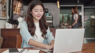 Kafede dizüstü bilgisayar üzerinde çalışan genç Asyalı serbest kadınlar. Asya mutlu kız barista garson gri apon giymek kafe veya restoranda iş kadın müşteri ye sıcak fincan kahve hizmet.