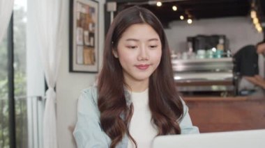Kafede dizüstü bilgisayar üzerinde çalışan genç Asyalı serbest kadınlar. Asya mutlu kız barista garson gri apon giymek kafe veya restoranda iş kadın müşteri ye sıcak fincan kahve hizmet.