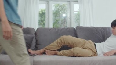 Genç Asya Gay çift kucaklamak ve evde öpücük. Çekici Asya Lgbtq gurur erkekler mutlu dinlenme oturma odası konseptinde kanepe yatarken birlikte romantik zaman geçirmek. Yavaş çekim Shot.