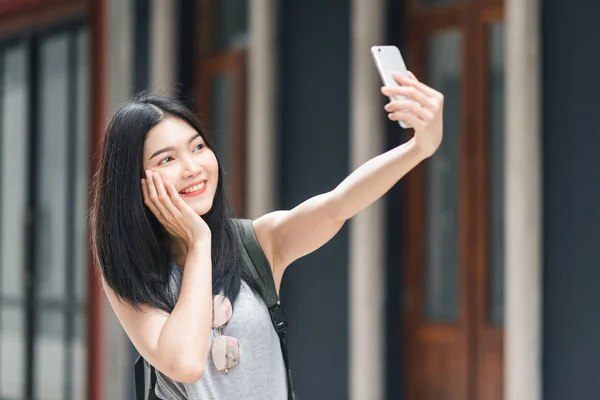Aasian bloggaaja nainen matkustaa Pekingissä, Kiinassa, backpacker nainen matkapuhelimella tehdä vlog ja elää sosiaalisessa mediassa viettäessään makeaa aikaa lomamatkalla. Naiset matkustavat kaupungilla käsite . — kuvapankkivalokuva