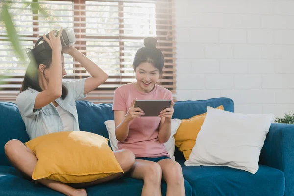 Unga lesbiska HBTQ asiatiska kvinnor par som använder Tablet hemma, Asiatisk älskare kvinnlig känsla glad kul och virtuell verklighet, VR spela spel tillsammans medan liggande soffa i vardagsrum hemma Concept. — Stockfoto