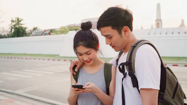 Traveler Asian couple direction on location map in Bangkok, Thailand, sweet couple using mobile phone looking on map while spending holiday trip in sunset. Lifestyle couple travel in city concept.