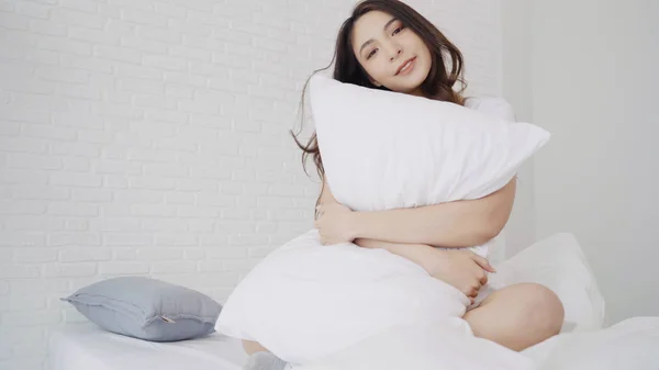 Boldog szép ázsiai nő felébred, mosolyogva és nyújtás a karját, az ágyában, a hálószobában. Fiatal ázsiai nő használata pihenni otthon. Életmód nő a haza fogalma. — Stock Fotó