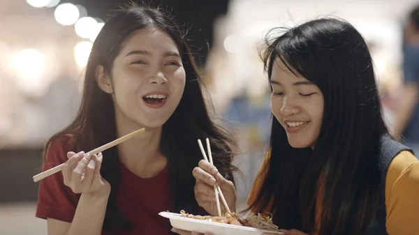 Les jeunes femmes asiatiques amis voyagent à Bangkok, Thaïlande, belle femme se sentant heureuse en marchant et en mangeant Pad Thai à The Khao San Road. Voyage femmes manger de la nourriture de rue en Thaïlande concept . — Photo