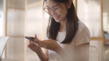 Ofiste cep telefonu kullanan serbest Asyalı kadınlar. Genç Japon Asya Kız işyeri kavramı masada internet üzerinden sosyal medya kontrol akıllı telefon kullanarak. Yavaş çekim.