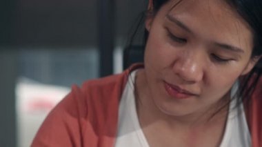 Genç Asyalı hamile kadın karnına ve ailesine not defterine bebek çiziyor. Anne kendini mutlu hissederken, pozitif ve huzurlu gülümserken çocuk evde oturma odasında kendine dikkat ederken..