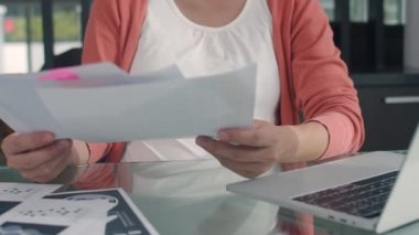 Genç Asyalı hamile kadın laptoptan gelir ve gider kayıtlarını kullanıyor. Baba karısının karnına dokunurken kayıt bütçesi, vergi, mali belge oturma odasında ev konseptinde çalışıyor..