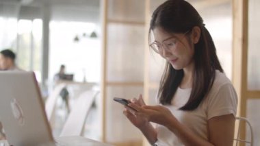 Ofiste cep telefonu kullanan serbest Asyalı kadınlar. Genç Japon Asya Kız işyeri kavramı masada internet üzerinden sosyal medya kontrol akıllı telefon kullanarak. Yavaş çekim.