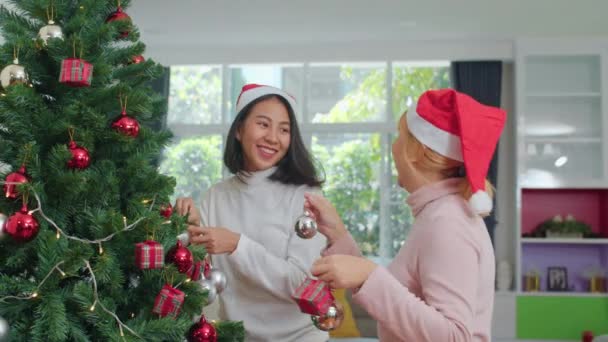 アジアの女性の友人は クリスマスフェスティバルでクリスマスツリーを飾ります 女性の十代の幸せな笑顔は 自宅のリビングルームで一緒にXmas冬の休日を祝います — ストック動画