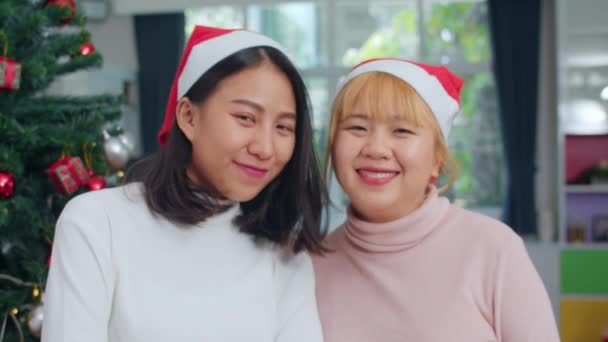 アジアのレズビアンのカップルはクリスマスフェスティバルを祝います Lgbtq女性の十代の若者は 自宅のリビングルームで一緒にクリスマス冬の休日を楽しむカメラを見て幸せな笑顔をリラックスクリスマス帽子を着用 — ストック動画