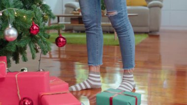 Asyalı kadınlar Noel festivalinde Noel ağacı süsler. Genç bir kadın kış tatilini evinde, oturma odasında kutluyor..