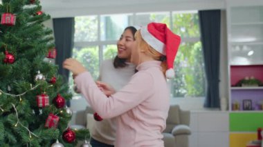 Asyalı kadın arkadaşlar Noel festivalinde Noel ağacı süsleyin. Kadın genç mutlu gülümseyerek evde oturma odasında birlikte xmas kış tatilleri kutlamak. Yavaş çekim çekimi.