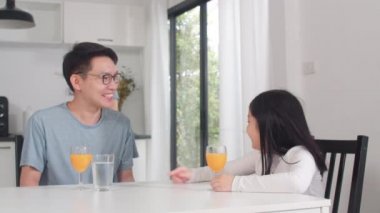 Asyalı Japon ailesi evde kahvaltı yapar. Asyalı mutlu baba, anne ve kız spagetti yer. Sabahları mutfakta portakal suyu içerler..