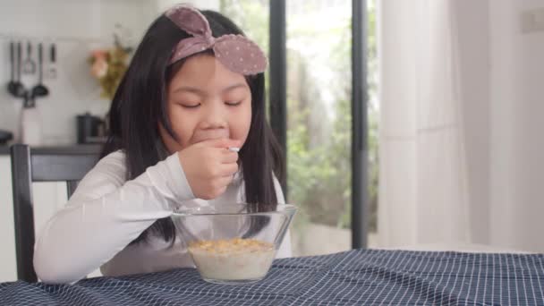 亚洲的日本女孩在家里吃早餐 在早上去学校之前 亚洲女人很高兴在厨房的桌子上吃玉米片和碗里的牛奶 慢动作射击 — 图库视频影像