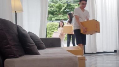 Mutlu Asyalı genç aile yeni bir ev aldı. Çinli anne, baba ve çocuk mutlu bir şekilde gülümsüyor. Büyük, modern bir evde hareket eden nesneler için karton kutular tutuyorlar. Yeni gayrimenkul konut, kredi ve ipotek.