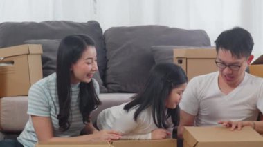 Mutlu Asyalı genç aile taşınmaları yeni bir eve yerleşiyor. Çinli ebeveynler ve çocuklar taşınma gününde karton kutuyu ya da paketi oturma odasında açarlar. Gayrimenkul konut, kredi ve ipotek.