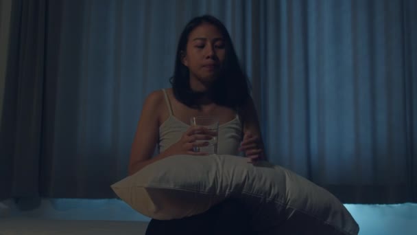 ベッドの上に座っている美しいアジアの若い女性は 寝室で睡眠薬や夜の薬を服用します 不健康なインドの女性は不眠症や頭痛に苦しんで 落ち込んで女の子は抗うつ薬を保持しています — ストック動画