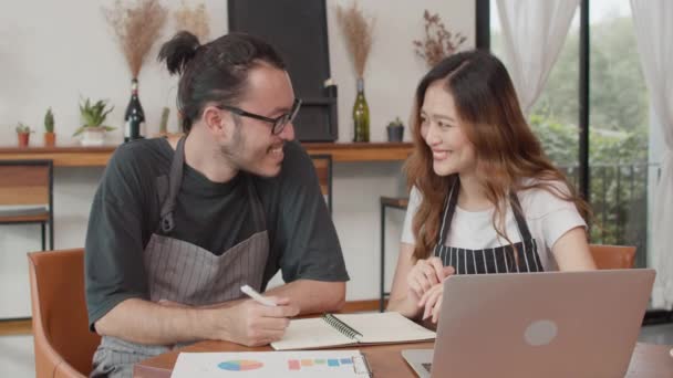 陽気なアジアの中小企業のオーナーは カフェで月のための店の文書でプロジェクトと金融を議論ノートパソコンを使用してカップル 女性と男性が書類作成を一緒に行い オンラインで税金を支払う — ストック動画