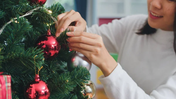 Ασιατικές γυναίκες διακοσμούν το χριστουγεννιάτικο δέντρο στο φεστιβάλ Χριστουγέννων. Θηλυκό έφηβος χαρούμενος χαμογελά γιορτάζουν Χριστούγεννα χειμερινές διακοπές στο σαλόνι στο σπίτι. Κοντινό πλάνο. — Φωτογραφία Αρχείου
