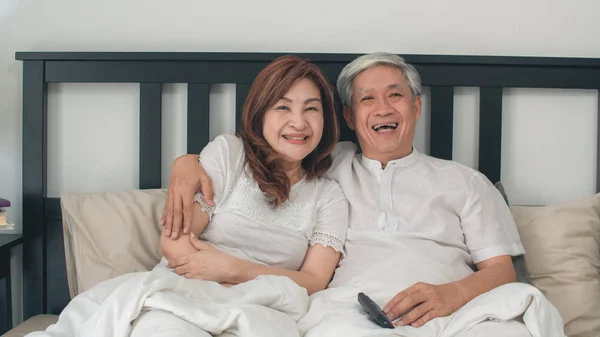 Asiatisches älteres Paar vor dem Fernseher im Schlafzimmer zu Hause, genießen asiatische Paar Liebe Moment, während sie auf dem Bett liegen, wenn zu Hause entspannt. Zeit genießen Lebensstil Senioren Familienkonzept. — Stockfoto