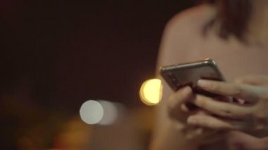 Genç gezgin Asyalı kadın, Bangkok 'ta bir gece eve cep telefonuyla gitmek için taksi çağırma başvurusunu kullanıyor. Öğrenci kız dışarıda dinlenirken internet üzerinden akıllı telefon sohbeti yapıyor..