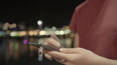 Gezgin Asyalı blogcu kadın, Bangkok 'ta sokak gecesinde seyahat ediyor. Genç bayan, cep telefonu kullanıyor. Şehirdeki nehrin yanında sosyal medyayı kontrol ediyor. Yaz tatili için Tayland 'a turist seyahati.