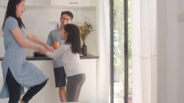 Mutlu genç Asyalı aile kahvaltıdan sonra evde müzik ve dans dinler. Çekici Japon anne baba ve kız çocuğu sabahları modern mutfakta birlikte vakit geçirmekten zevk alıyorlar..