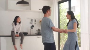 Mutlu genç Asyalı aile kahvaltıdan sonra evde müzik ve dans dinler. Japon anne ve kız çocuğu sabahları modern mutfakta birlikte vakit geçirmekten zevk alıyorlar. Yavaş çekim.
