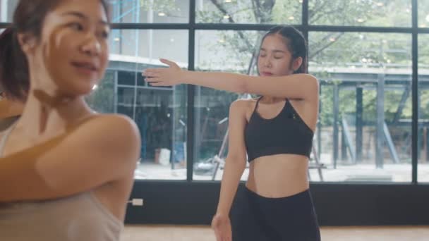 インストラクターとヨガのレッスンを練習若いアジアのスポーティな魅力的な人々 フィットネススタジオで健康的なライフスタイルを行使する女性のアジアグループ スポーツ活動 体操やバレエダンスクラス — ストック動画